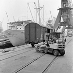 854157 Afbeelding van het overladen van goederen uit een goederenwagen op een kade in de haven van Rotterdam ...